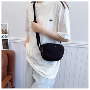 Close-up of a minimalist black shell-shaped crossbody bag with a silver metal DD logo