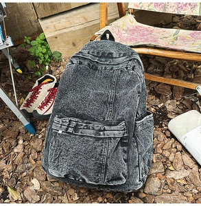 Detail of vintage denim backpack with washed texture in an outdoor camping setting