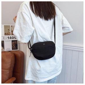 Detail of a black half-moon nylon bag with silver DD logo and adjustable shoulder strap