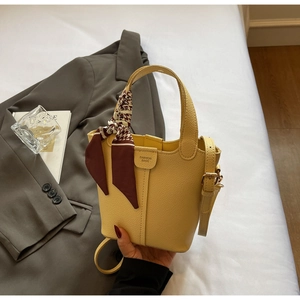 Close-up of yellow pebbled leather bucket bag with houndstooth silk scarf on handle