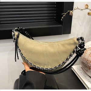Detail of beige crescent bag featuring vertical stitching, rope knot strap and silver chain