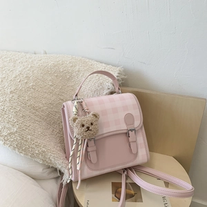 Detailed view of pink plaid backpack with brown bear charm and silk scarf decoration