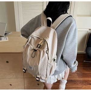 Side view of a beige nylon backpack with adjustable straps in a modern study room