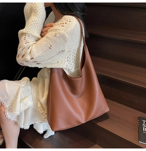 Dettaglio della grande borsa hobo marrone in pelle martellata su sfondo di legno