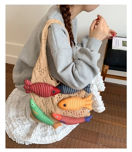 Detail of hand-knit crochet tote bag featuring colorful plush fish charms for women