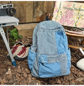 Detail of patchwork denim backpack with blue denim fabric and front zipper pocket