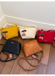 Detail of five mini crossbody bucket bags in various colors with cherry charms