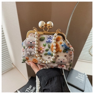 Detailed close-up of a vintage shell bag with pearl chain handle and floral teddy bear print