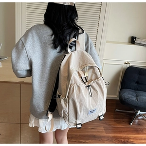 Detailed back view of a khaki lightweight nylon backpack featuring a drawstring front pocket
