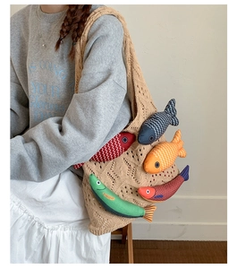 Detailed close-up of beige knitted tote bag with colorful 3D stuffed fish decorations