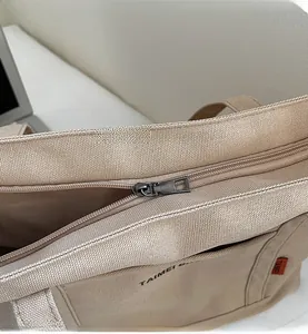 Dettaglio della cerniera in metallo scorrevole su una borsa tote in tela kaki resistente
