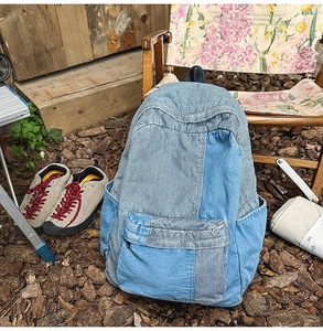 Detail view of a vintage denim patchwork backpack with corduroy accents in an outdoor setting