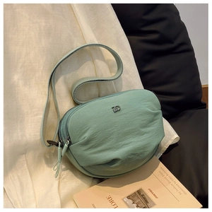 Detail of mint green nylon crossbody bag with metal DD logo and double zipper closures