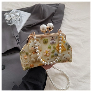 Detail of shell bag with teddy bear print, pearl handle, and large pearl kiss lock