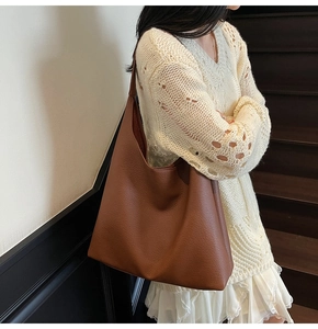 Borsa hobo in pelle marrone indossata da una modella in un ambiente interno elegante