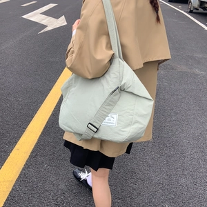 Outdoor shot of light green canvas tote bag with adjustable strap and woven label detail