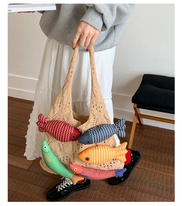 Close-up of beige knit tote bag featuring colorful 3D stuffed fish and hollow crochet design