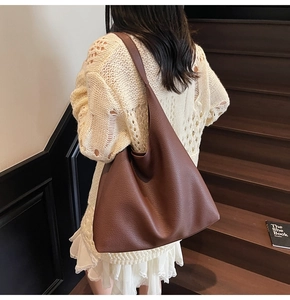 Vista dettagliata della borsa tote in pelle martellata marrone scuro sul maglione