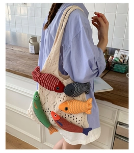 Detail of knit tote bag featuring five colorful 3D stuffed fish dolls in a cafe setting