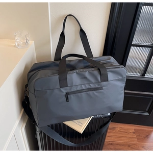 Dettaglio del borsone da viaggio grigio con logo NOCOBAG su una valigia nera
