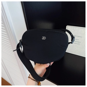 Detail of black nylon crossbody bag with silver metal logo and wide textile strap