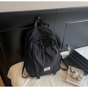 Detail of black nylon backpack with drawstring pocket and metal buckle in home setting