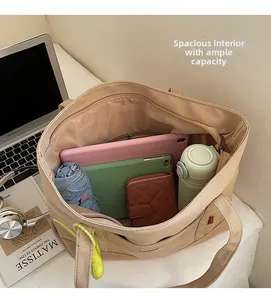 Dettaglio dell'interno spazioso della borsa tote in tela kaki con vari oggetti personali