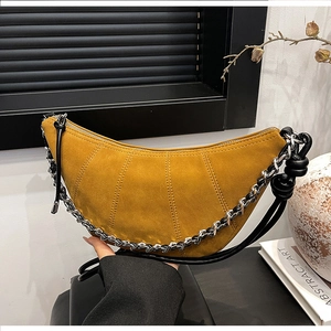 Detail of yellow suede crescent bag with pleated stitching and silver chain strap
