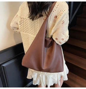 Vista laterale di una grande borsa tote in pelle marrone martellata indossata da una modella
