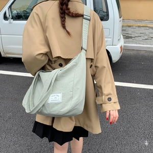 Outdoor back view of a large light green canvas tote bag with adjustable shoulder strap