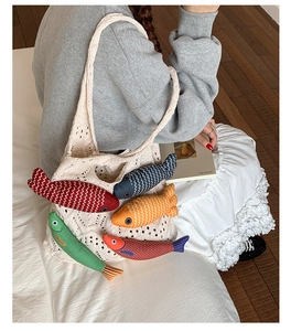 Detail of knit tote bag featuring colorful 3D stuffed fish charms and crochet hollow texture