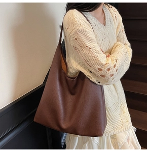 Borsa tote hobo in pelle marrone indossata da una modella in un ambiente interno accogliente