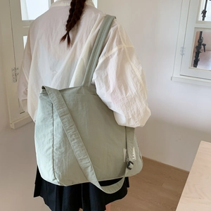 Detail of light green canvas tote bag showing soft fabric texture and dual shoulder straps