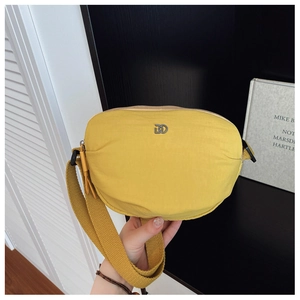 Close-up of yellow crescent crossbody bag showing nylon texture and metal logo detail