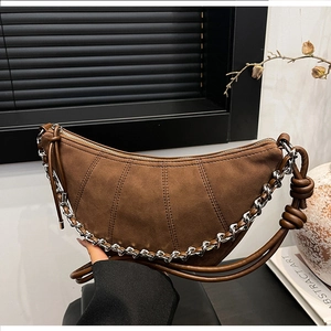 Detail of dark brown hobo bag with patchwork stitching and silver chain strap