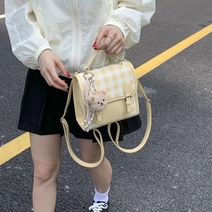 Detail of yellow checkered crossbody bag with cute teddy bear charm and woven rope accent