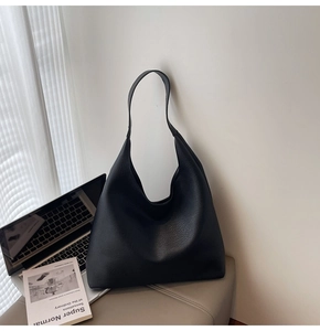 Dettaglio della borsa hobo grande nera in pelle martellata su una scrivania minimalista