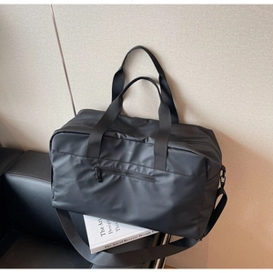 Dettaglio di borsa da viaggio nera impermeabile con tracolla su un divano in pelle nera