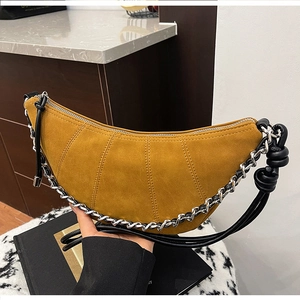 Detail of yellow suede croissant bag featuring quilted texture and knot strap design