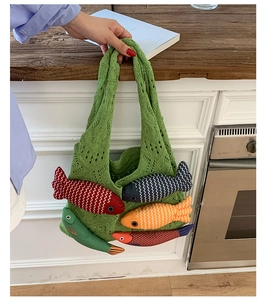 Detail of green knit tote bag featuring colorful 3D stuffed fish charms and crochet texture
