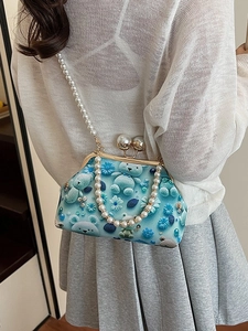 Blue shell bag with pearl chain strap and floral bear print worn by a model