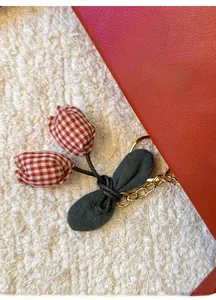Macro shot of handmade tulip fabric keychain with red plaid flower buds and green leaves