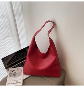 Elegante borsa tote in pelle rossa con trama litchi accanto a un laptop per il lavoro