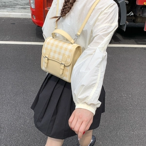 Detail view of yellow plaid crossbody bag with twin-buckle flap and long shoulder strap