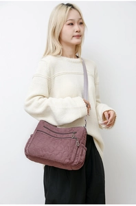 Detail of dusty pink nylon crossbody bag featuring heart-shaped quilted pattern and multi-pockets