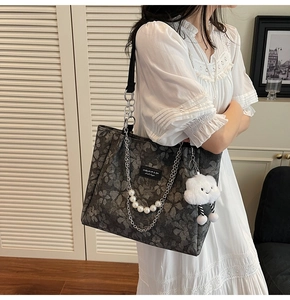 Detail of dark grey floral jacquard tote bag with silver chain and white plush charm