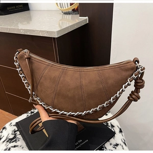Detail of brown suede crescent bag with silver chain strap and knotted shoulder design