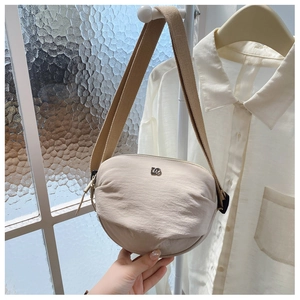 Detail of beige nylon half-moon crossbody bag featuring textured fabric and wide strap