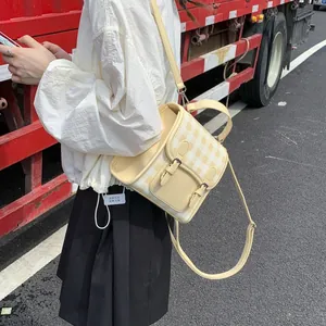 Detail of yellow and white checkerboard crossbody bag with vintage buckles and handle