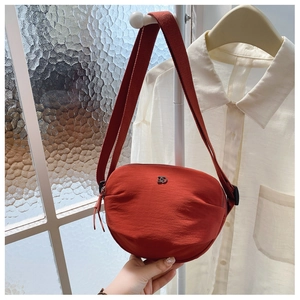Detail of brick red nylon crescent bag with silver DD logo and adjustable wide strap